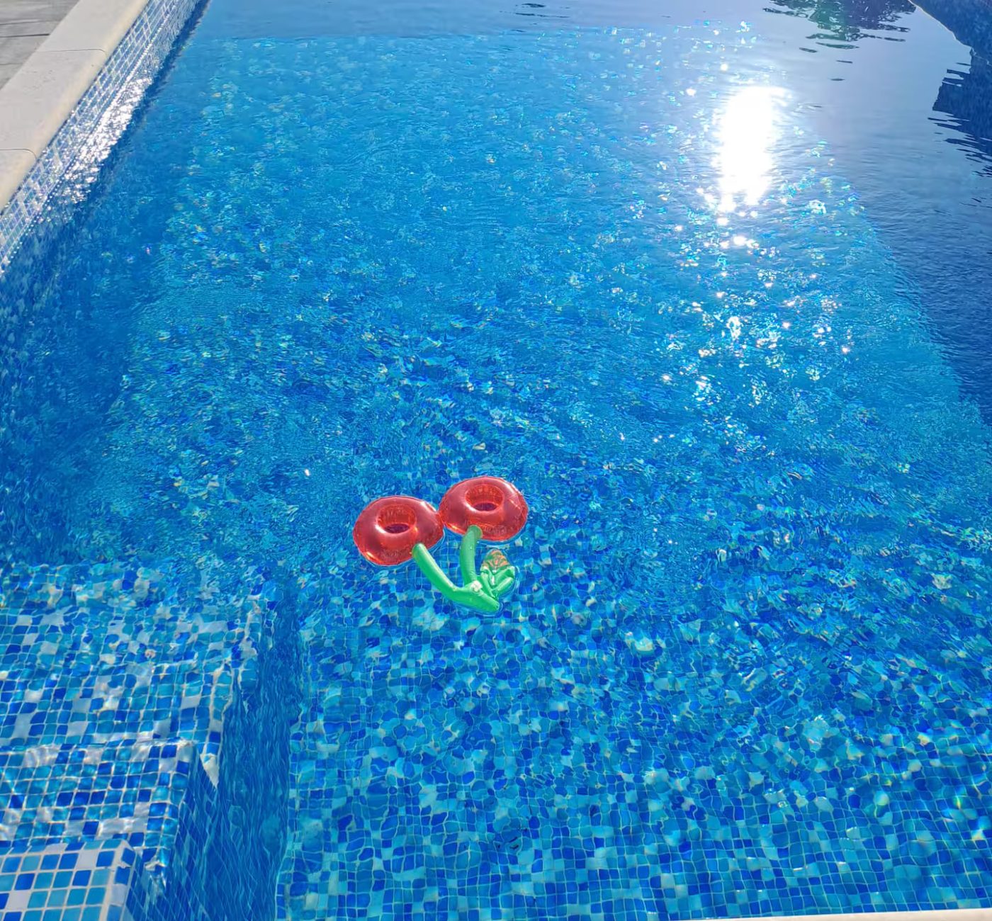 An image of a swimming pool with a small cherry float